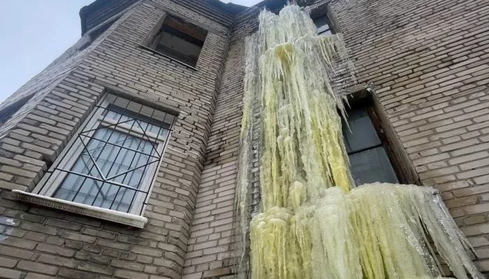 Замерзший и сросшийся с домом водопад желтого цвета обнаружен в Барнауле. Фото